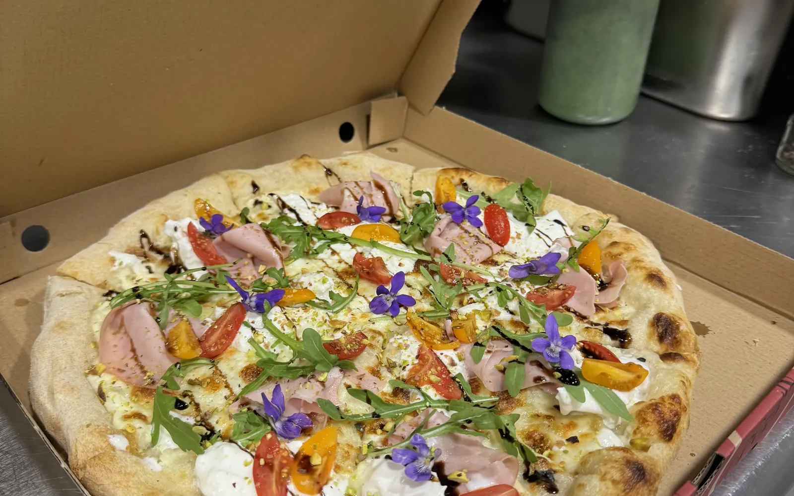 Pizza aux fleurs comestibles de Pizza L'Escapade, sortie du four à bois